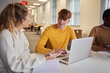 Students studying on a laptop and talking.