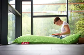 A student studying whilst sat on a beanbag in the library