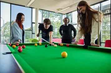 Four students playing pool in the students union.