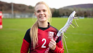 Student holing a lacrosse stick and wearing a USW Women’s Lacrosse tshirt.