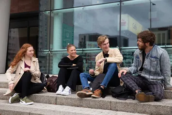 Four students sat on steps outside the Cardiff Campus.
