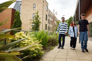 A group of students walking past the accommodation buildings and talking.
