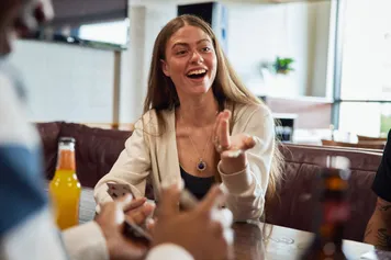 A student sat smiling and talking to friends off camera in Treforest Student's Union