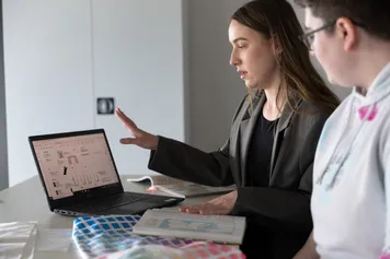 Two people looking at a laptop in conversation