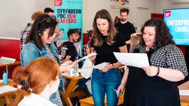 A group of students at a careers event holding papers preparing for a group presentation