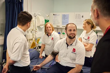A group of students taking the blood pressure reading of another student whilst a lecturer observes