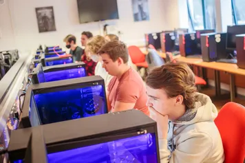 computing students sitting in a row, using computer facilities to work