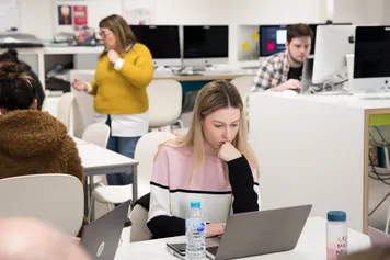 graphic communications students working in the design studio at laptops
