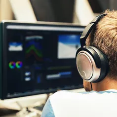 Student with headphones editing footage on a computer