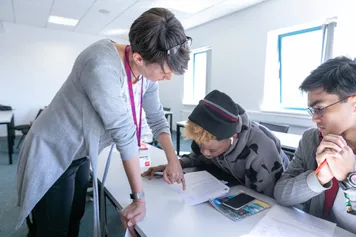Academic staff talking to students in class