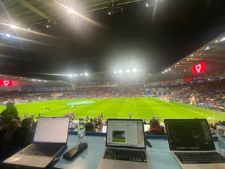Three laptops pictured in the stands of a sports match that are being used for Sports Journalism reporting.