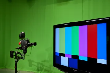 A screen and camera can be seen on in a TV studio setting.