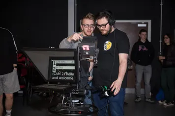 Two media production students using tv recording equipment in a tv studio