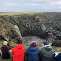 A group of natural history students sat overlooking a view of mountains
