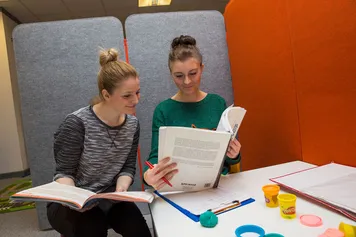 Two students reading from a textbook