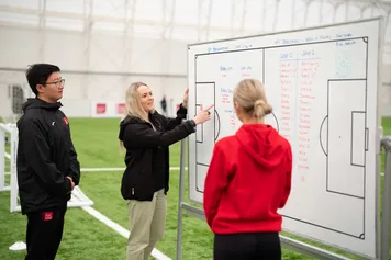 Students are looking at a white board discussing game techniques.