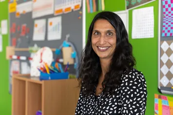 A student on a teaching placement in a classroom, smiling at the camera