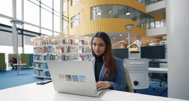 A student sat in newport library on her laptop