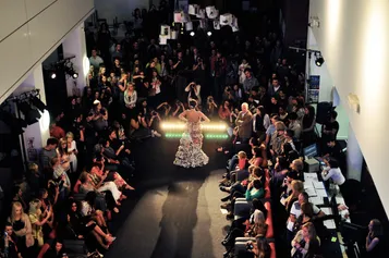 A crowd is cheering and taking photos of a model doing a catwalk.