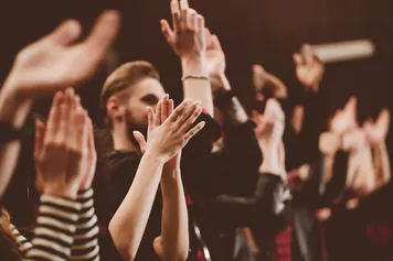 A group of people in a drama studio clapping