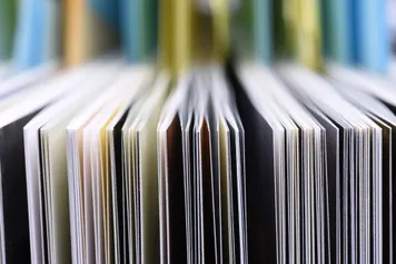 A close up of journals stood up on a bookshelf with their pages facing outwards
