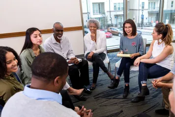 Stock image of a group sat around in a circle talking and listening to eachother