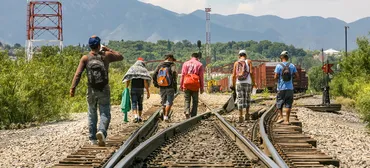 A group of refugees walking together along railroad tracks,