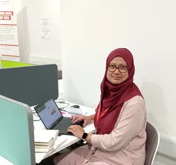 PhD student Farjana sitting in front of a laptop