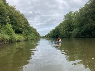 PhD Theatre and Performance student, Lucy, lying on a paddle on a board and smiling at camera