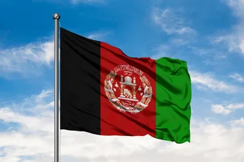 The Afghanistan flag on a pole against a blue sky