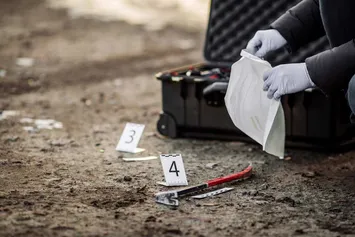Gloved hands inspecting evidence at a crime scene.