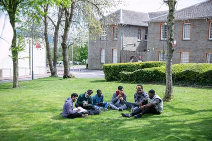 A group of international students sat on the grass in treforest campus