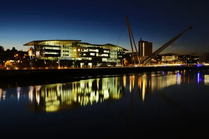 A riverside view of the Newport Campus at night.
