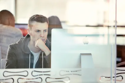 A person sitting at a computer in the Newport library behind a glass screen.