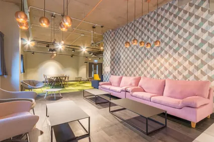 Part of the sitting area in Lumis, featuring a pink sofa and low hanging ceiling lights