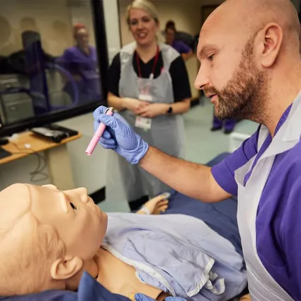 A student nurse checking the Human Patient Simulator's pupil reactions