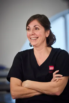 Nursing lecturer stands with her arms crossed in the clinical simulation centre