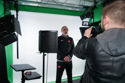 CELT media team member standing in front of a white background and filming equipment