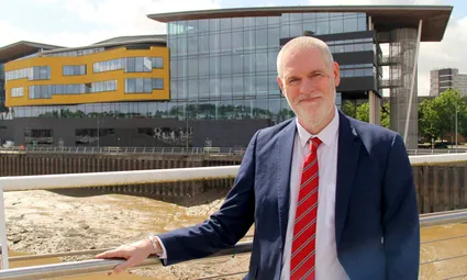 Dr Ben Calvert, Vice Chancellor, is smiling in front of the USW Newport campus.