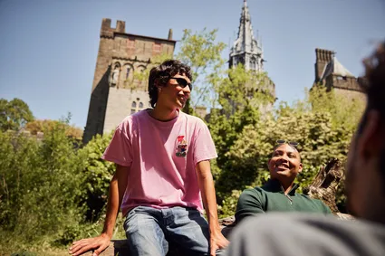 A group of students sitting, smiling in the sun in Bute Park.