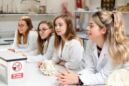group of international wildlife biology students in lab looking at skulls