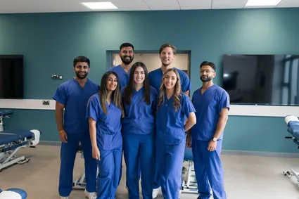 group photo of 7 chiropractic students in their uniforms in the chiropractic facilities