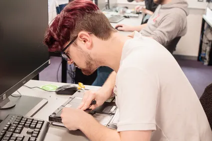 cyber security student working at computer with equipment