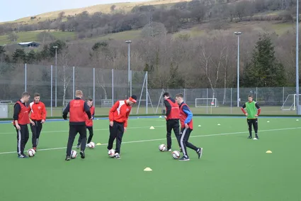 Sport students playing football on a football pitch.