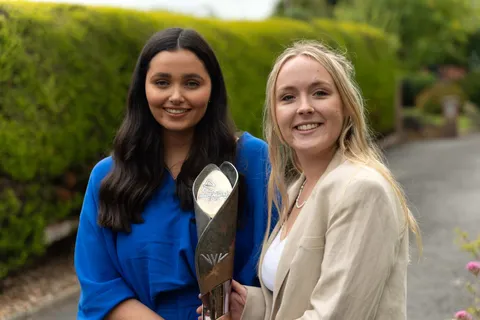 bethan jones and olivia soady standing with commonwealth games trophy