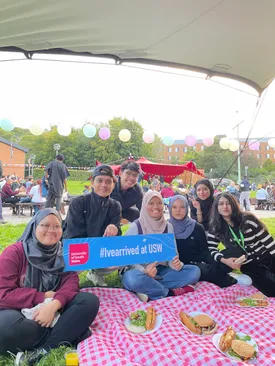 A group of international students sat on the grass in treforest campus