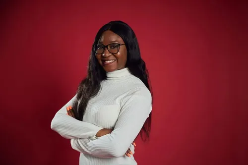 Accounting student Joelle, smiles at camera with her arms crossed, in front of a red backdrop