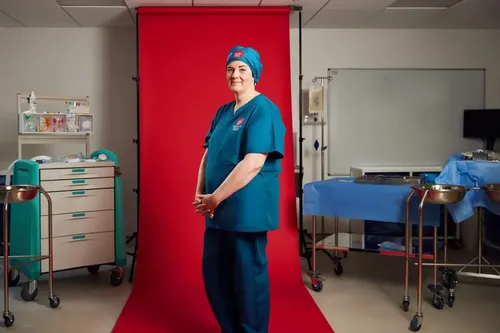 Allied Health student n scrubs stands confidently in front of a vibrant red backdrop.