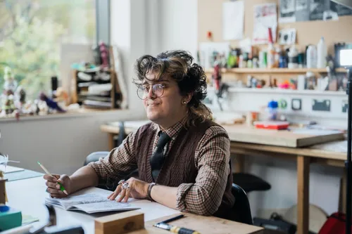 A student sitting at a desk with pen and paper, immersed in their animation studies and creative process.