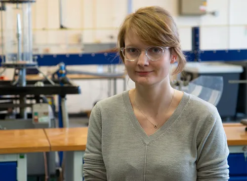Mechanical Engineering graduate Bethany Jones smiling at camera in front of engineering equipment